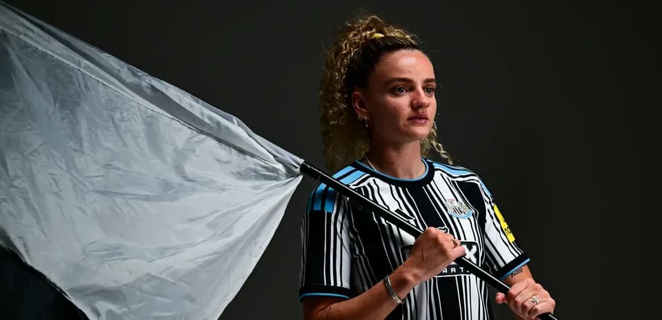Jugadora con camiseta de Newcastle sosteniendo una bandera