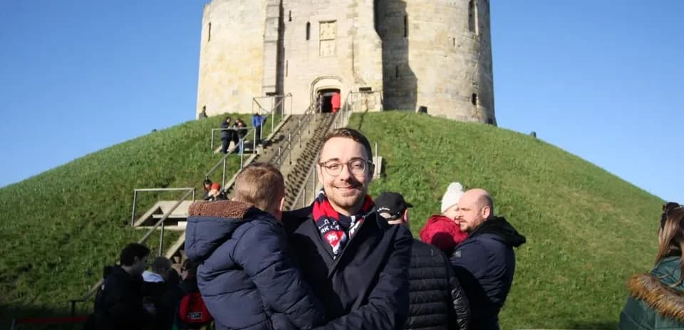 Hombre sosteniendo a un niño frente a una torre