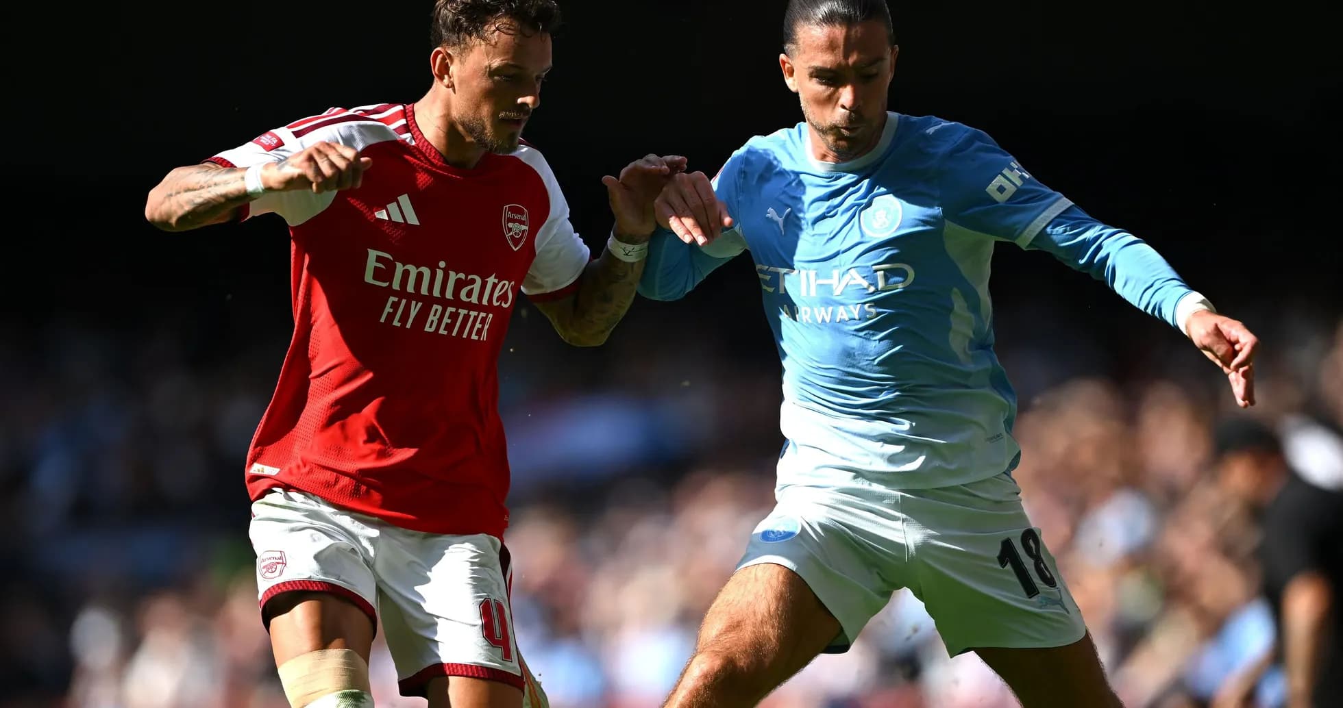 Jugadores de Arsenal y Manchester City compitiendo por el balón
