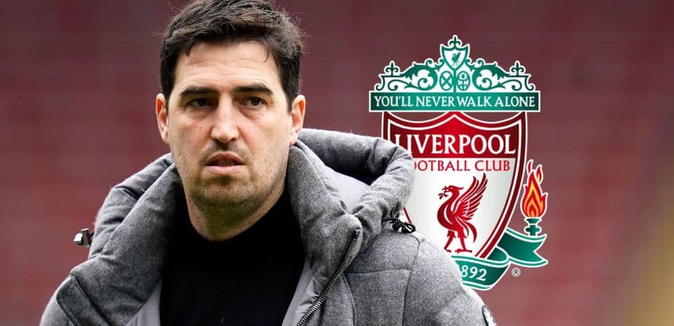 Entrenador con abrigo frente al escudo de Liverpool