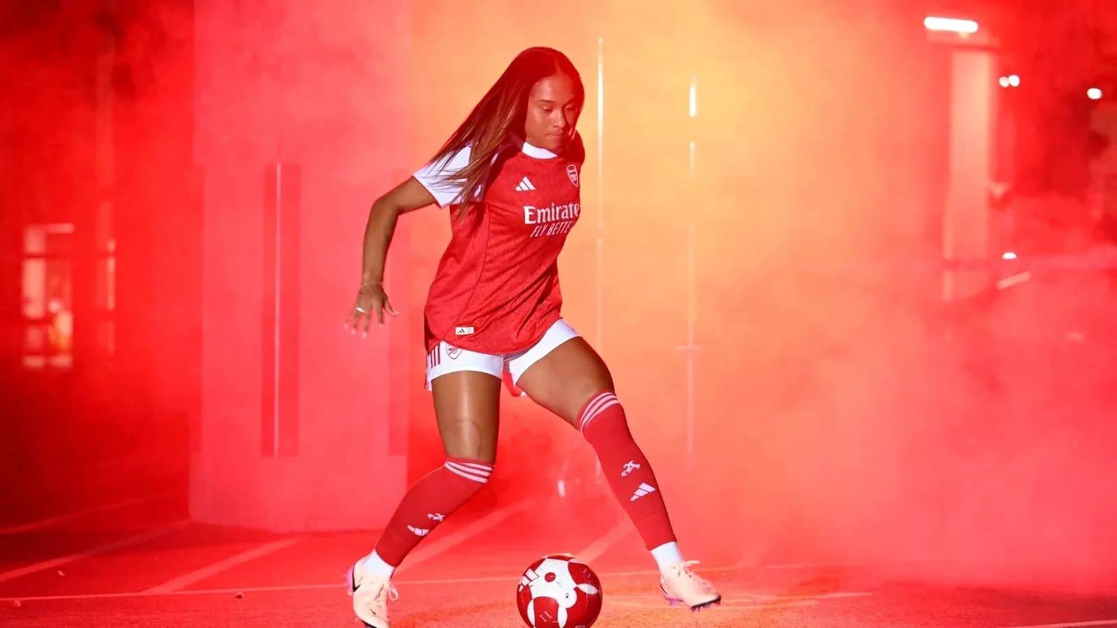 Jugadora de fútbol con balón en humo rojo