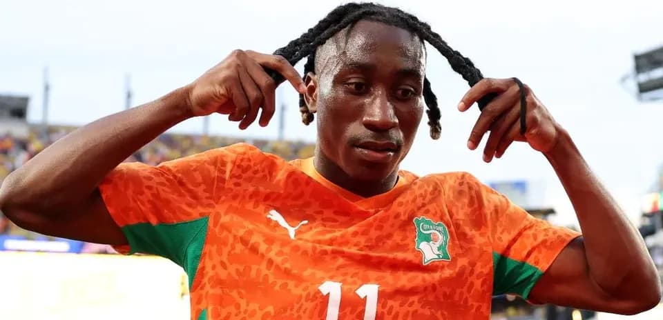 Jugador de fútbol ajustando su cabello en el campo
