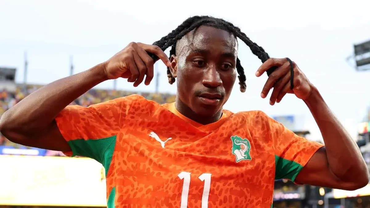 Jugador de fútbol ajustando su cabello en el campo