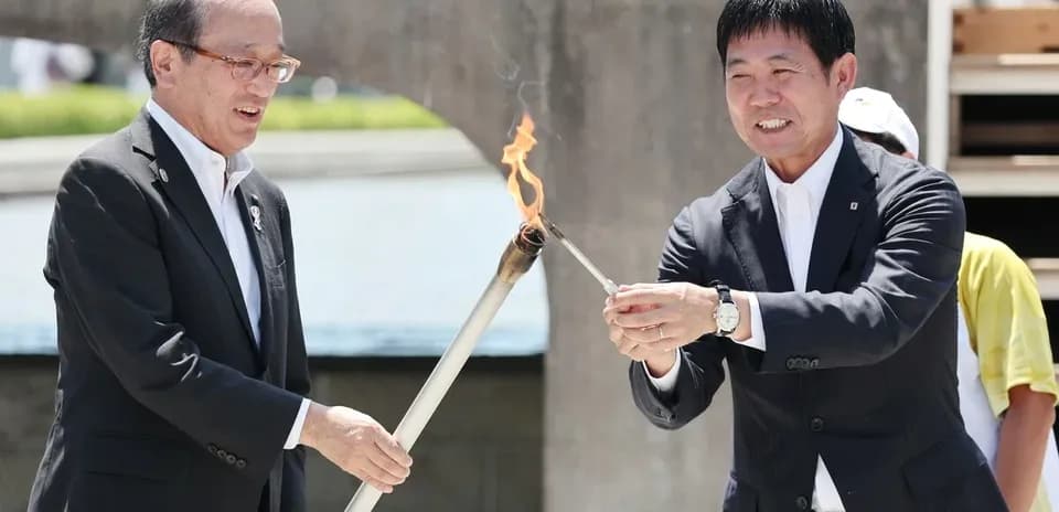 Dos personas encendiendo una antorcha en ceremonia