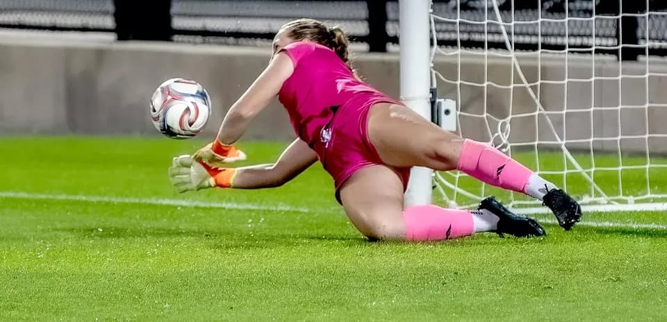 Portera intentando detener el balón en la portería