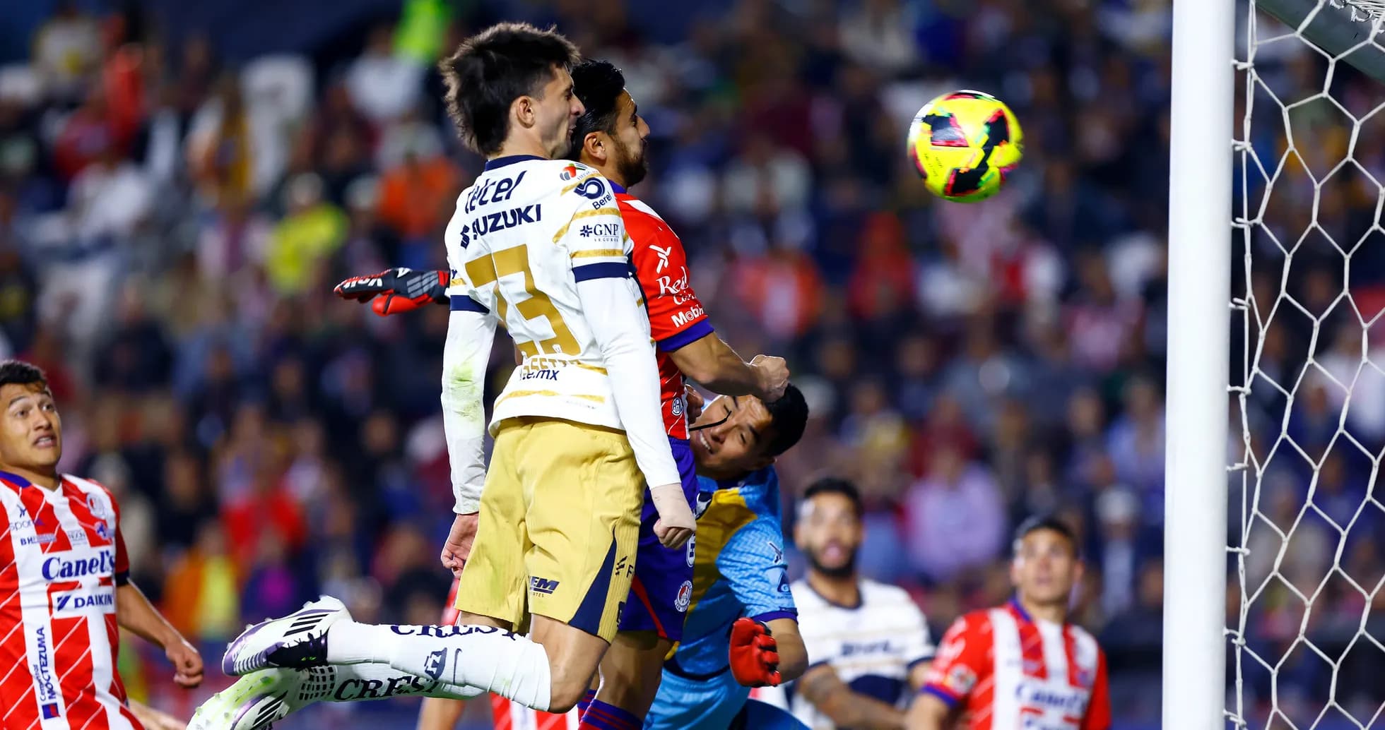 Jugadores de Pumas saltando por el balón
