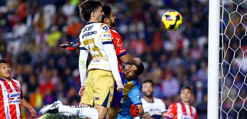 Jugadores de Pumas saltando por el balón