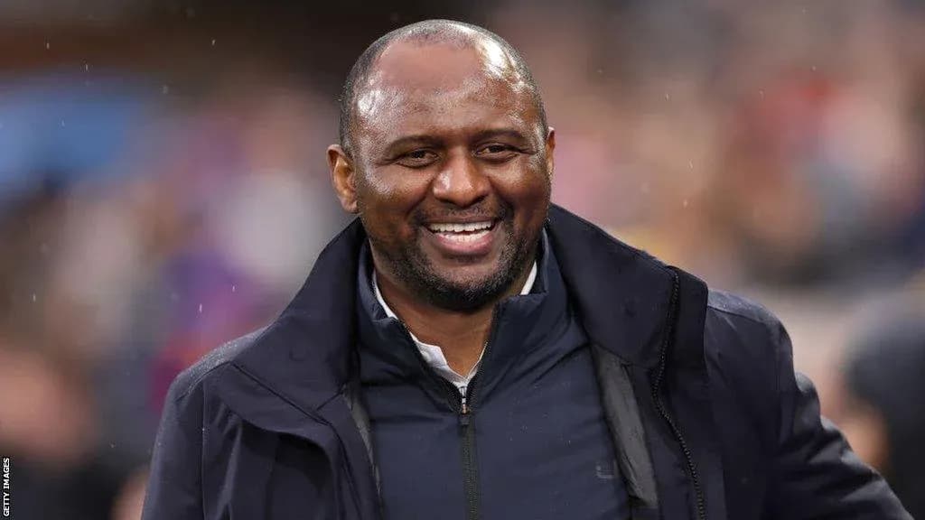 Entrenador sonriendo en el banquillo durante el partido