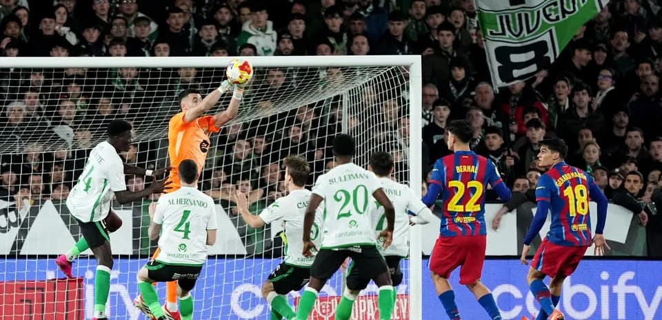 Portero deteniendo un balón en el área de gol