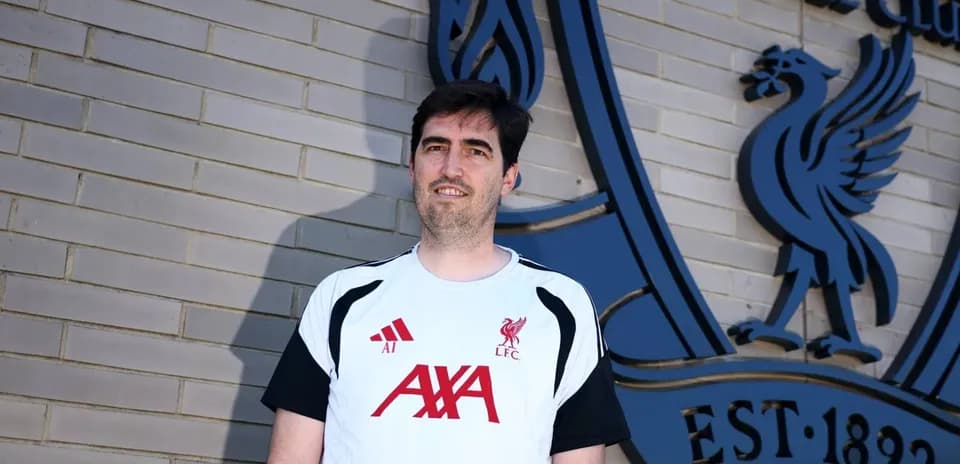 Entrenador posando frente al logo de Liverpool FC