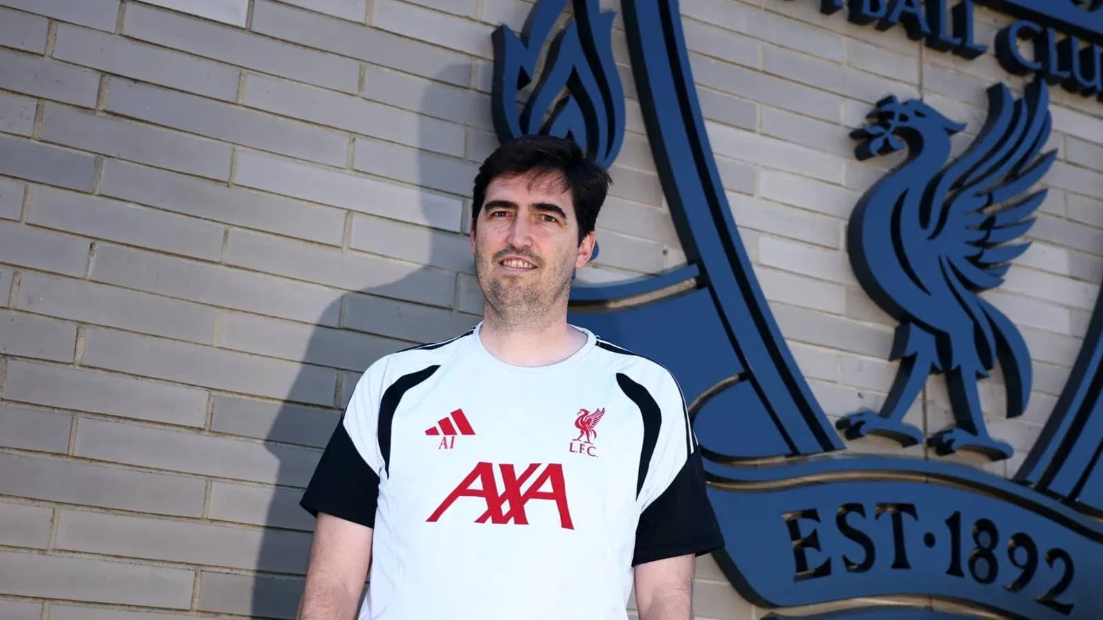 Entrenador posando frente al logo de Liverpool FC