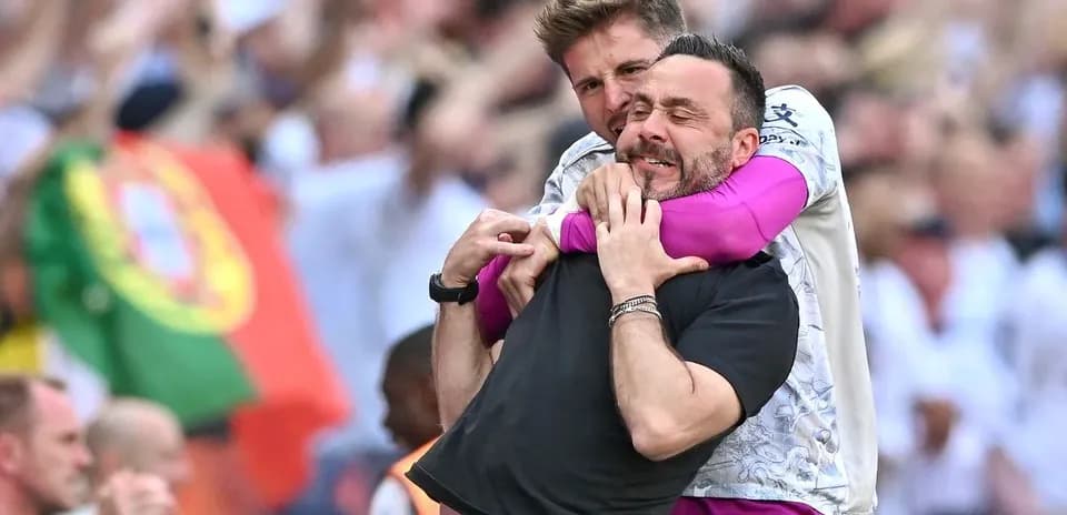 Entrenadores celebrando con un abrazo en el estadio