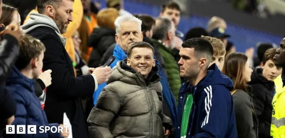 A young boy smiling near a group of spectators