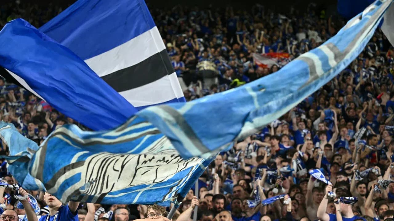 Aficionados ondeando banderas y bufandas en el estadio