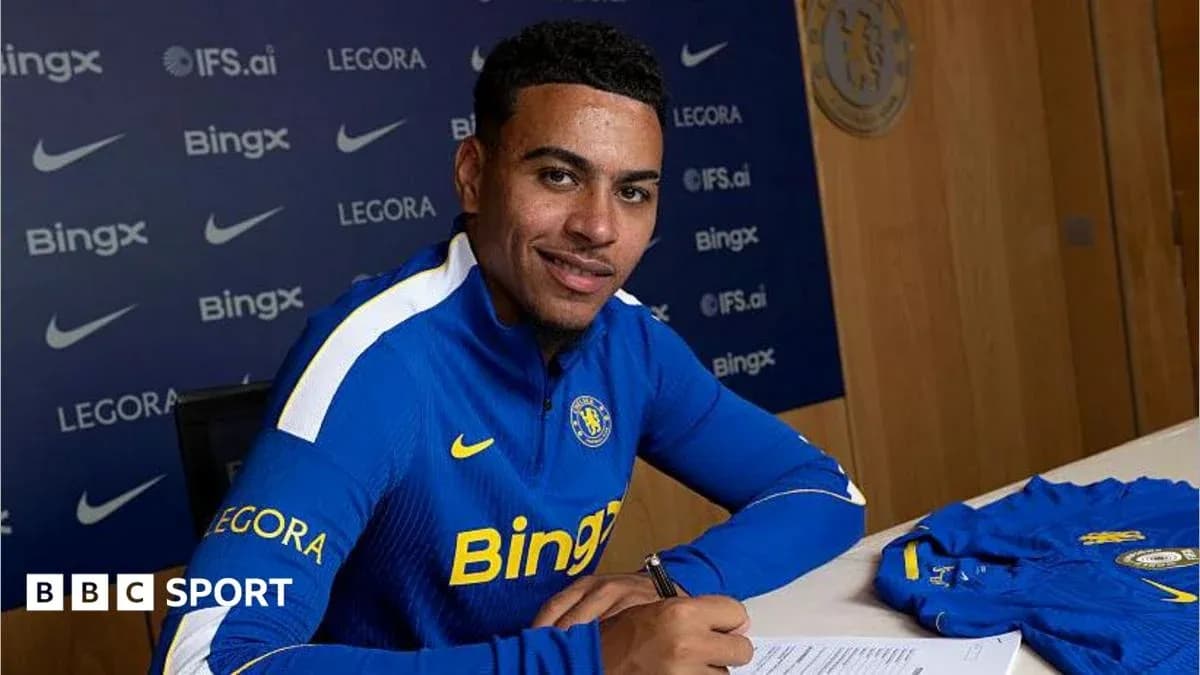 Jugador firmando contrato en mesa con camiseta