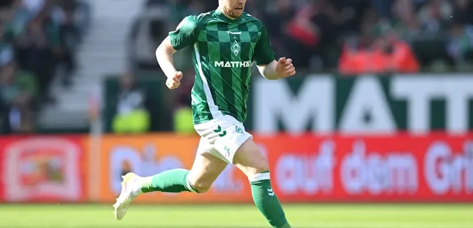 Jugador corriendo con balón en el campo de fútbol