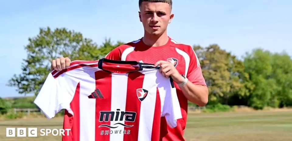 Jugador sosteniendo camiseta de Cheltenham Town en el campo