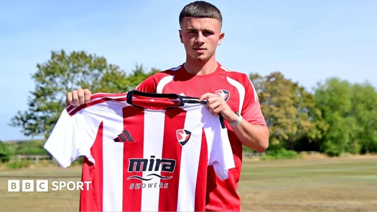 Jugador sosteniendo camiseta de Cheltenham Town en el campo