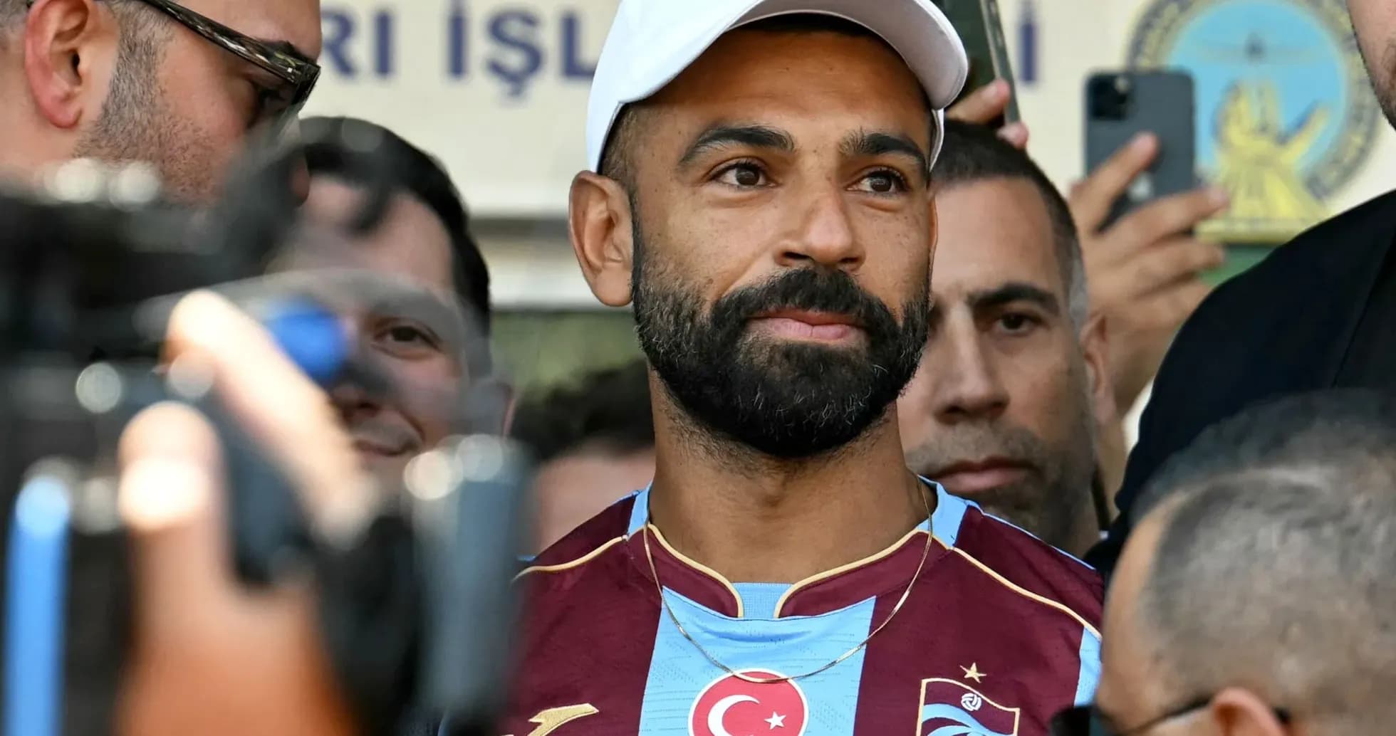 Jugador de fútbol en camiseta de Trabzonspor rodeado de personas