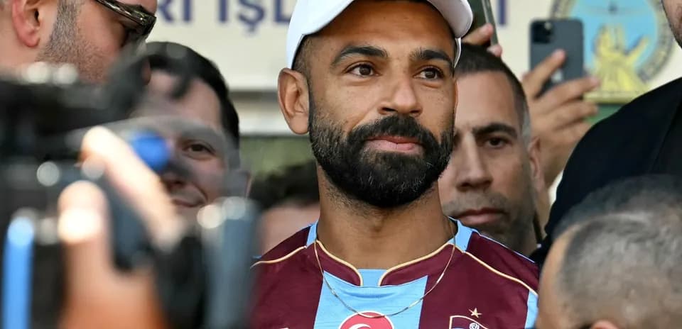 Jugador de fútbol en camiseta de Trabzonspor rodeado de personas