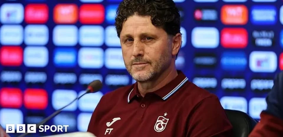 Entrenador en conferencia de prensa con fondo gráfico