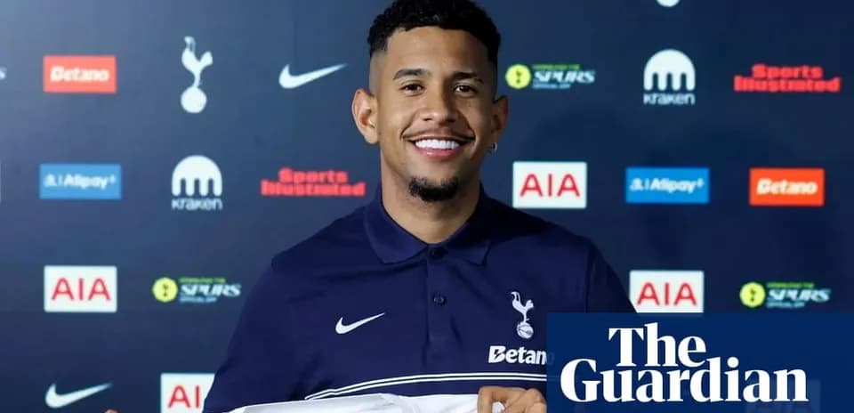 Jugador sonriente sosteniendo camiseta de Tottenham