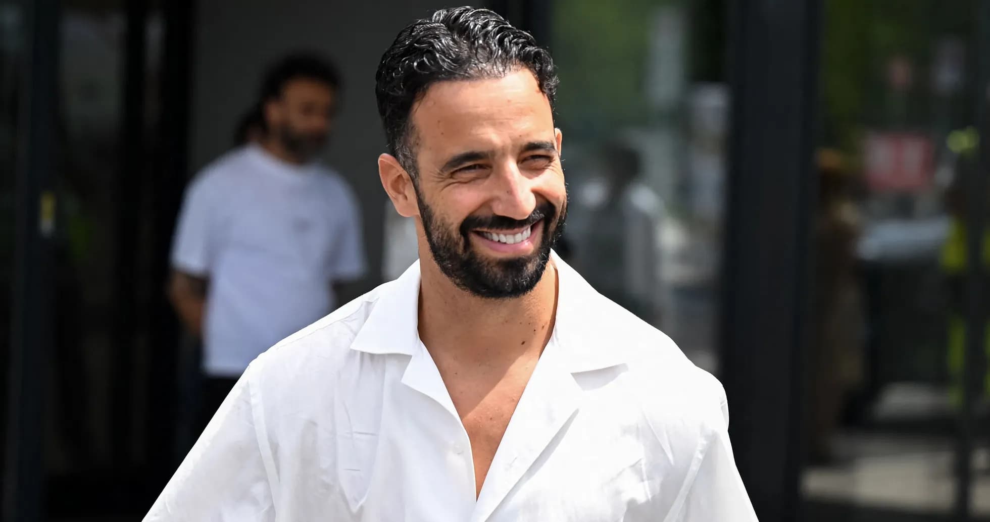 Hombre sonriendo con camisa blanca en la calle