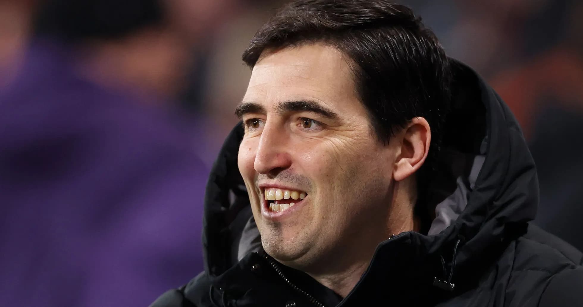 Entrenador sonriendo en el banquillo durante el partido