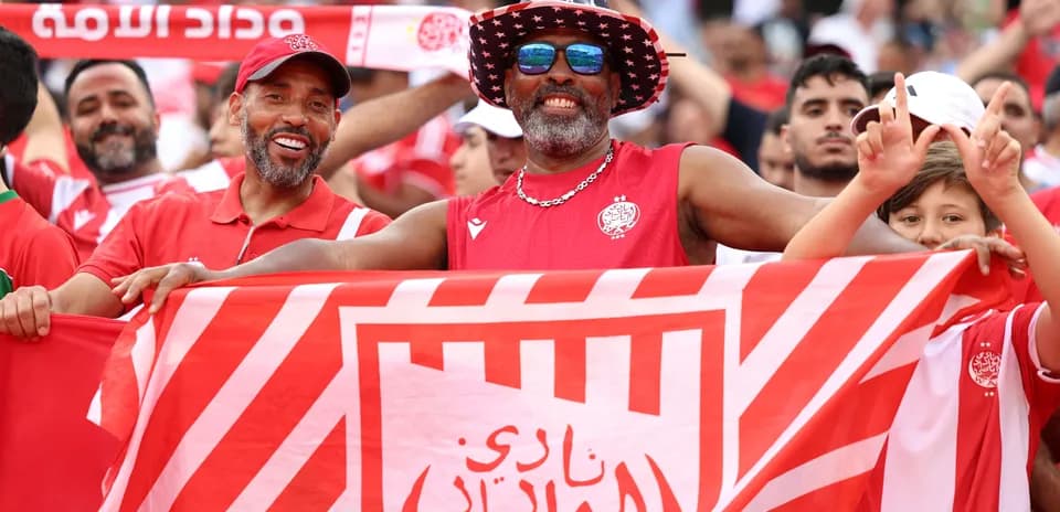 Aficionados celebrando con bandera del Wydad Casablanca