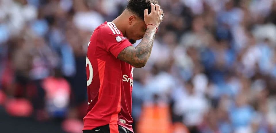Jugador con camiseta roja sosteniendo la cabeza en el campo