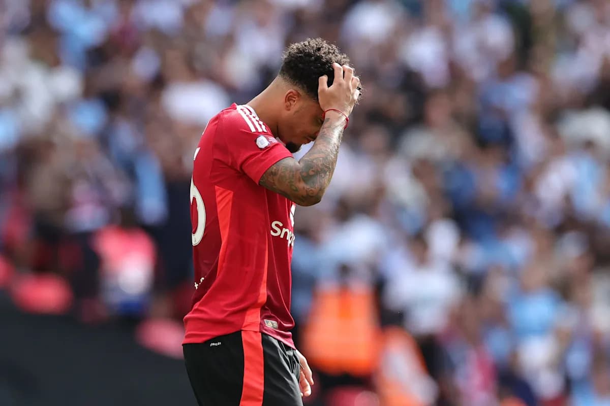 Jugador con camiseta roja sosteniendo la cabeza en el campo