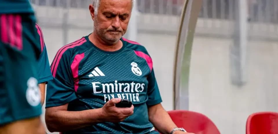 Entrenador sentado revisando su teléfono en el banquillo