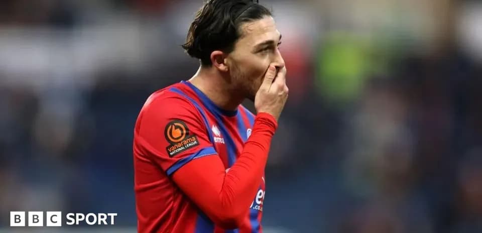 Jugador con camiseta roja sosteniendo su cara en el campo