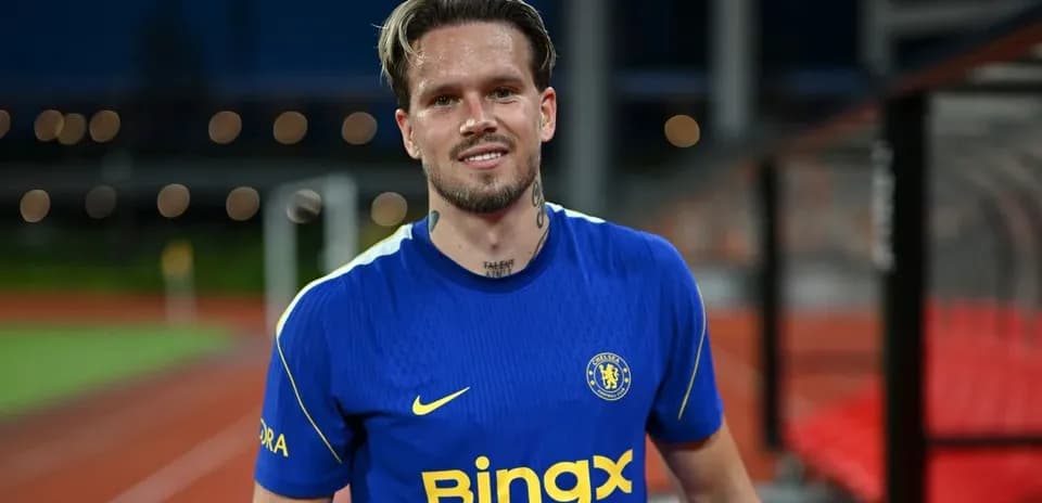Jugador sonriendo en camiseta del Chelsea en el campo