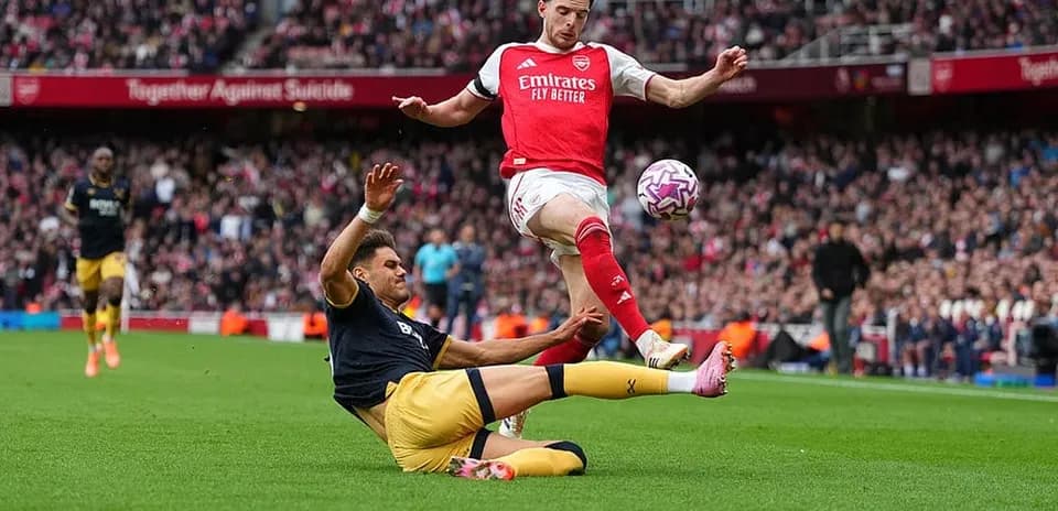 Jugador de Arsenal saltando sobre oponente de West Ham