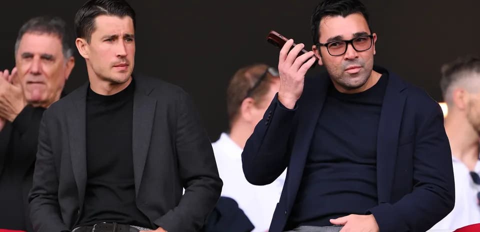 Dos hombres sentados en un evento deportivo