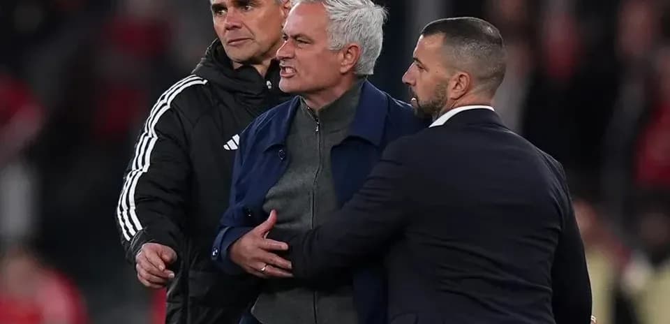 Entrenador siendo contenido por dos asistentes durante partido