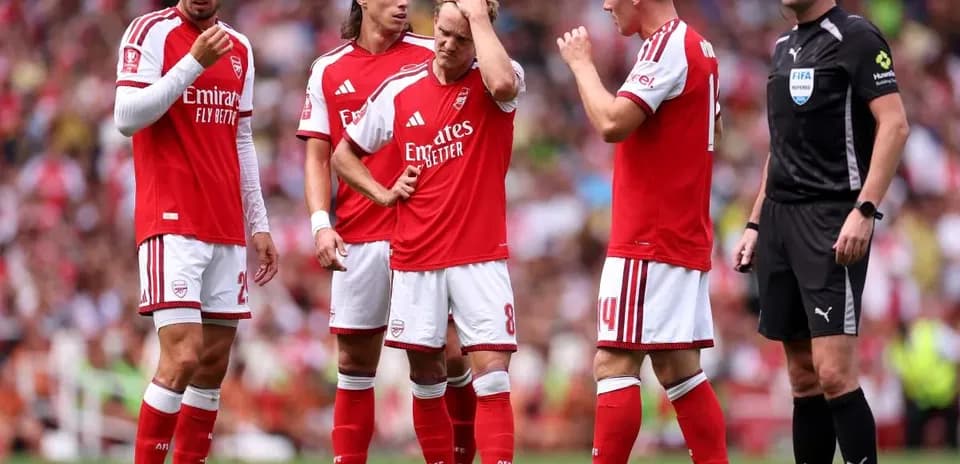 Jugadores de Arsenal discutiendo con el árbitro en el campo