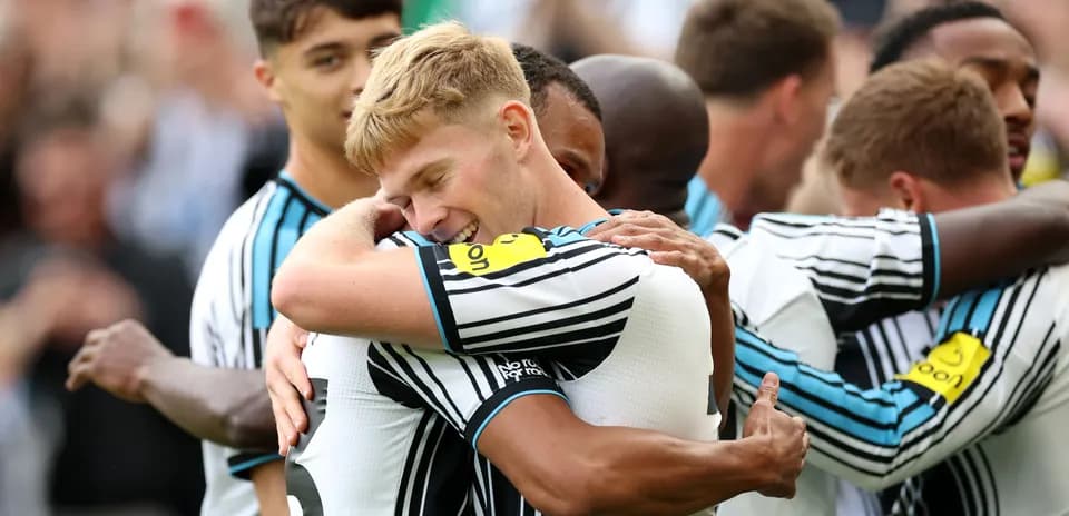 Jugadores de Newcastle United celebrando un gol abrazados