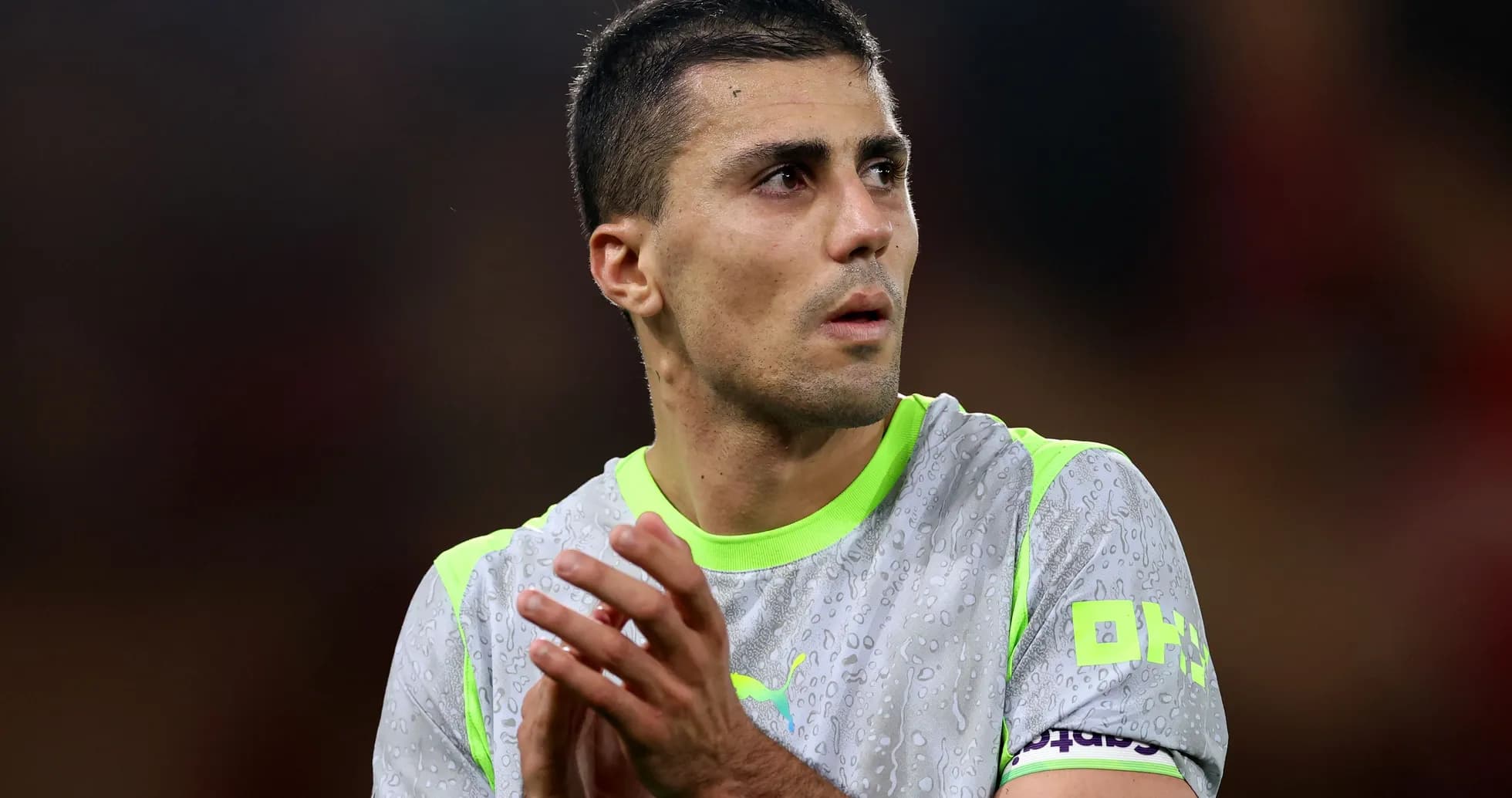 Jugador aplaudiendo con camiseta gris y detalles verdes