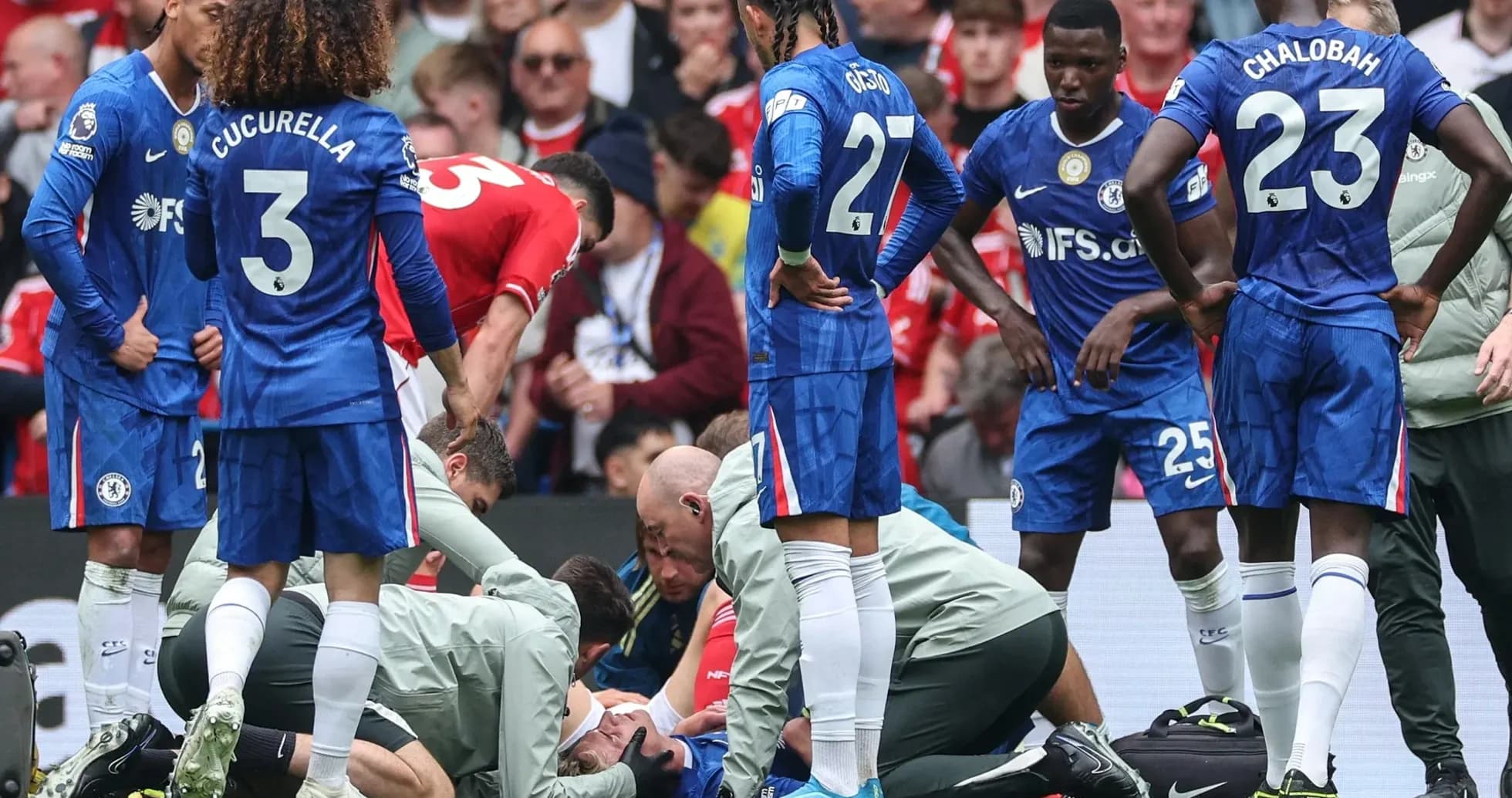 Jugadores de Chelsea rodeando a un compañero herido