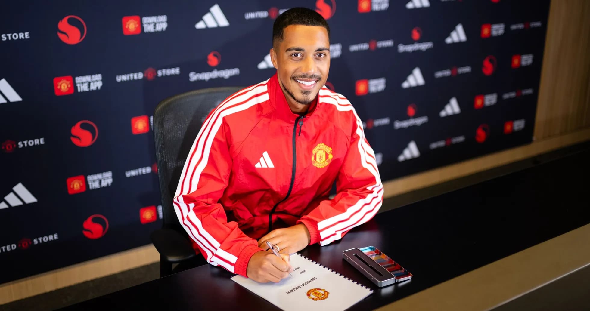 Jugador de Manchester United firmando contrato en mesa