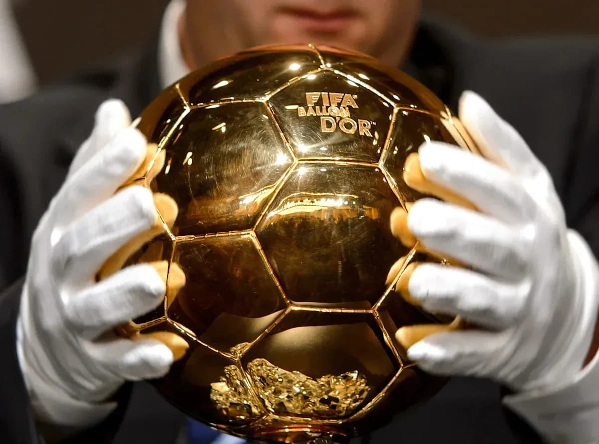 Balón de Oro sostenido por manos con guantes
