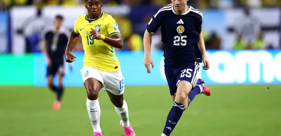 Jugador de Escocia corriendo con balón, seguido por brasileño