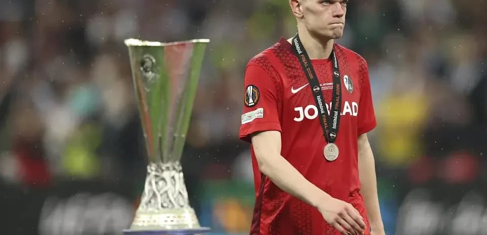 Jugador con medalla caminando junto a trofeo de Europa League