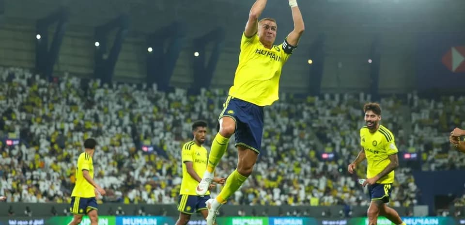Jugador saltando en celebración con equipo detrás