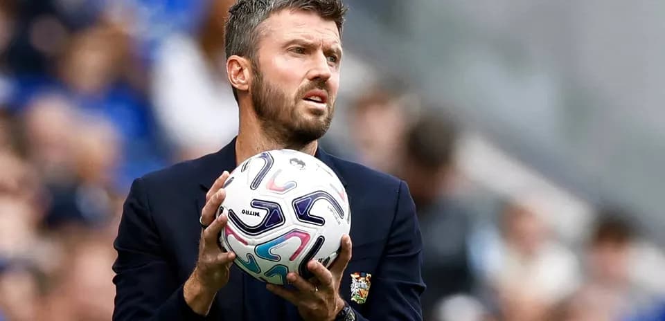 Entrenador sosteniendo un balón de fútbol durante el partido