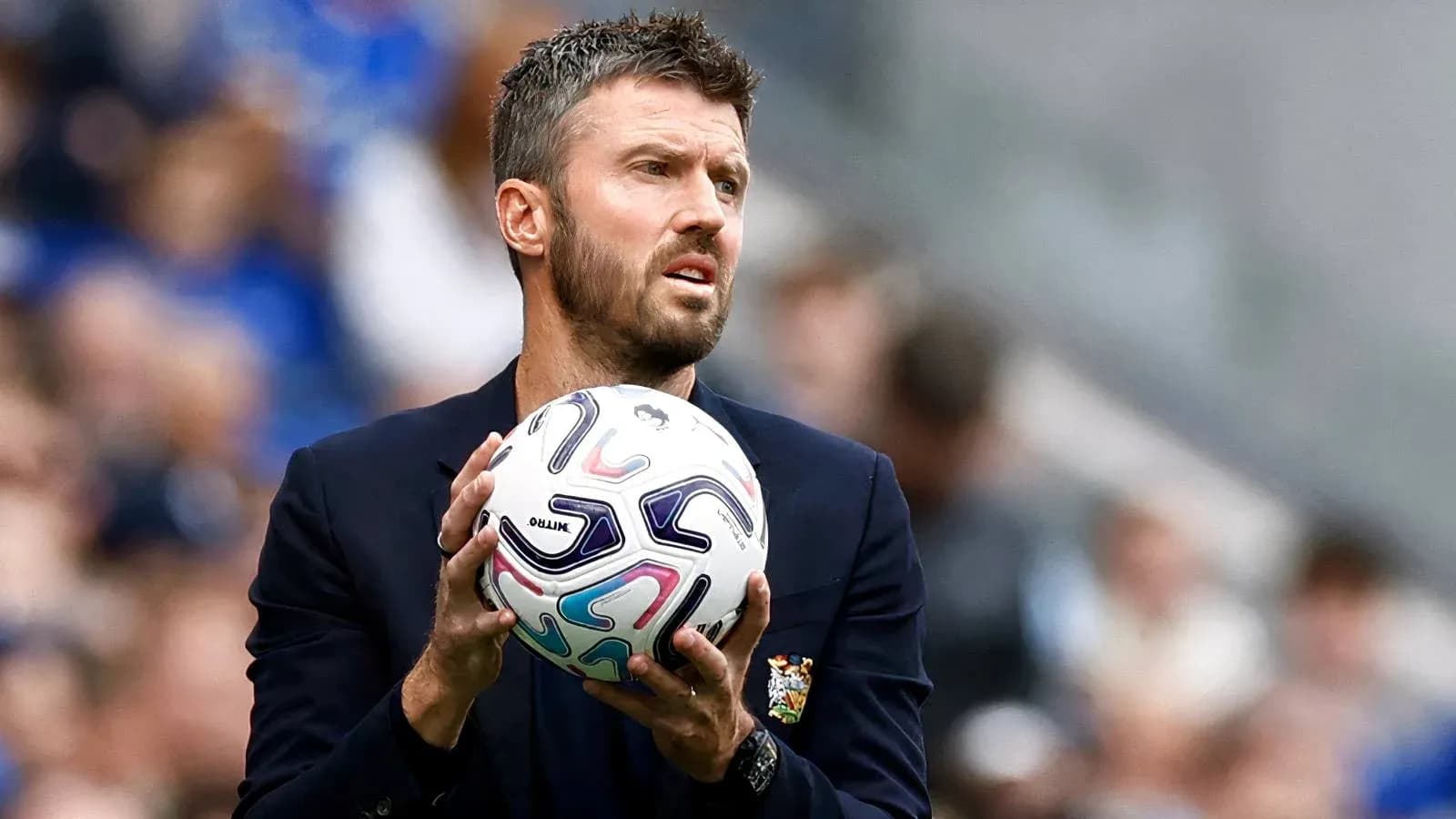 Entrenador sosteniendo un balón de fútbol durante el partido