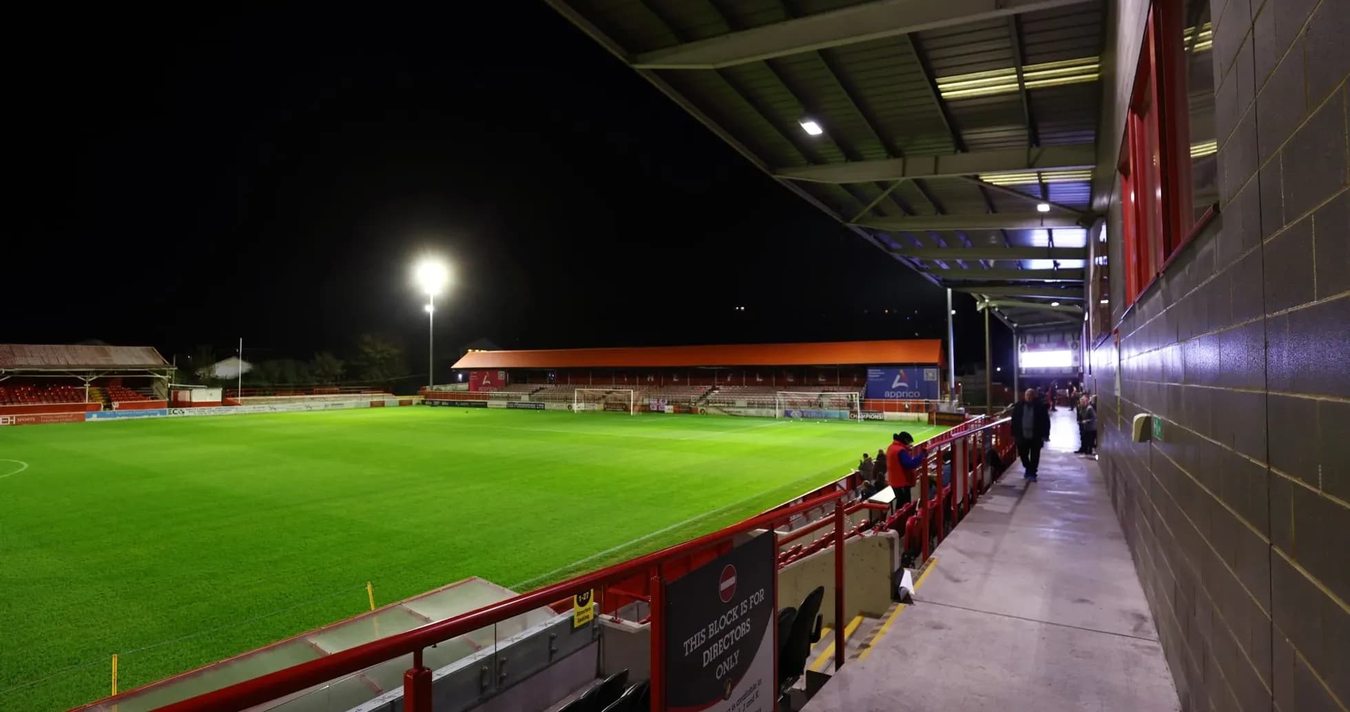 Estadio iluminado con césped y gradas vacías