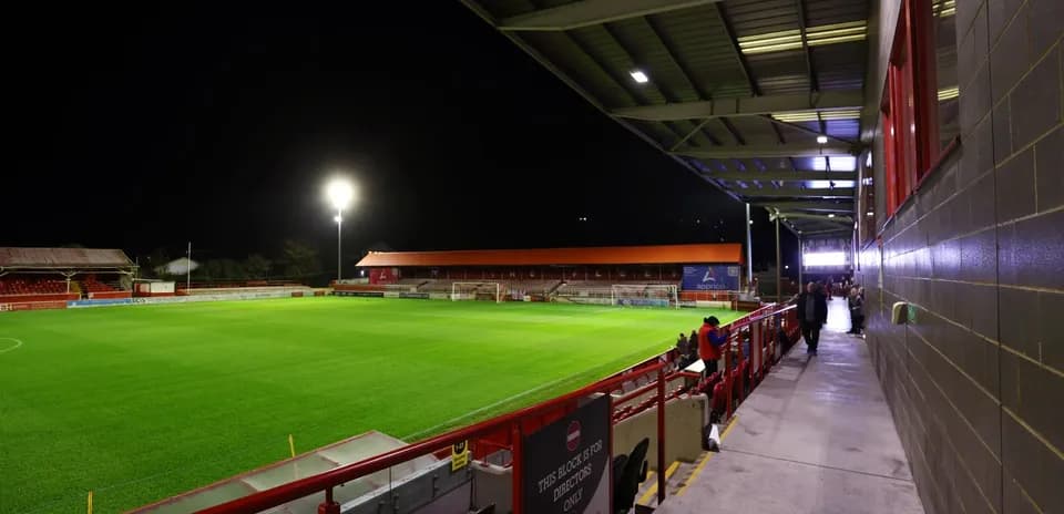 Estadio iluminado con césped y gradas vacías